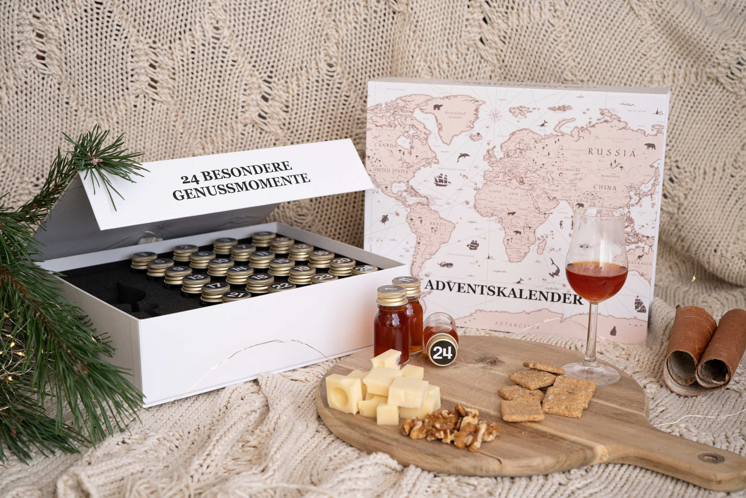 Halb Geöffnete Tasting Box neben einem Brettchen mit Käse und einer Whiskey Probe Verpackung von Achilles mit Druckveredelung einer Weltkarte für Produktproben oder Adventskalender